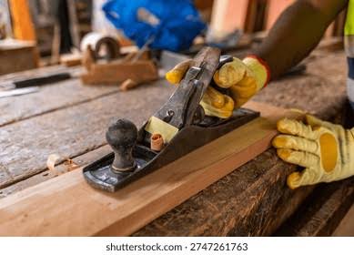 A hand plane taking a fine shaving from an oak board